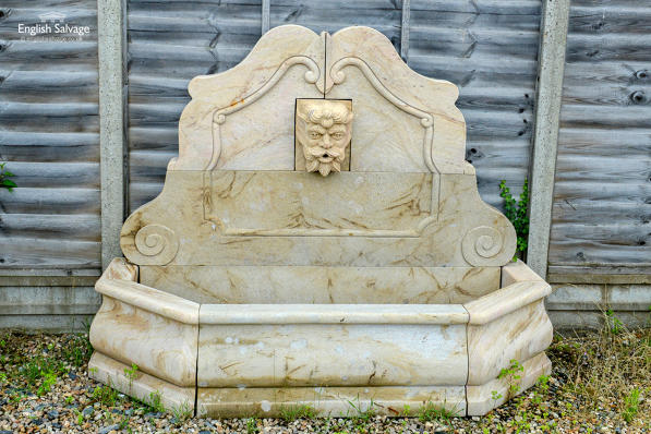 Stone wall fountain with bearded man spout